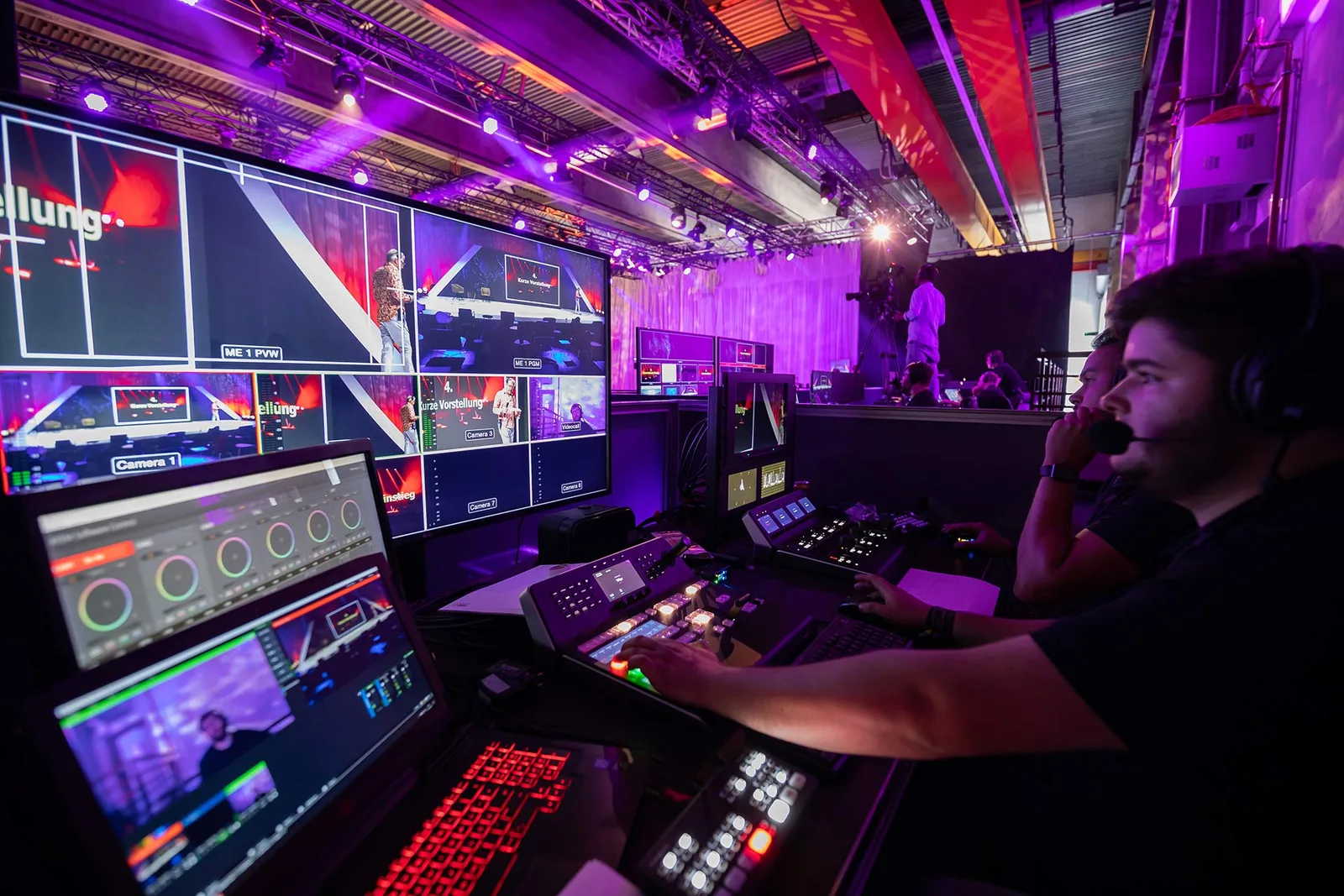 Techniker bedient Mischpult vor Videowall bei Live-Event mit Bühnenlicht
