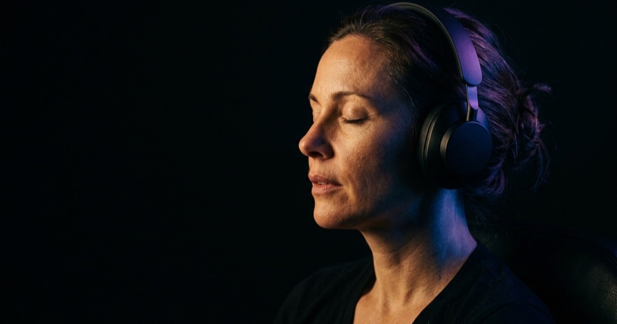 Frau mit Kopfhörern in entspannter Haltung, blaues Licht, Hypnobreath Atemtechnik