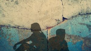 Zwei Personen-Silhouetten an einer Mauer mit Rissen, Liebeskummer-Metapher