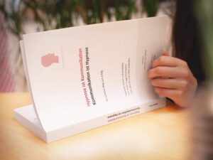 Offenes Buch mit rotem Hypnose-Logo und Text zur Kommunikation