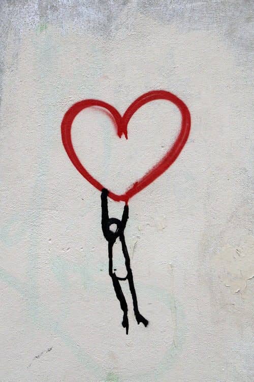 Graffiti: Person hält großes rotes Herz, Wandmalerei