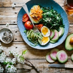 Gesunde Salatschüssel mit Gemüse, Ei und Kräutern in blauer Schale