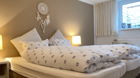 Fotografie Schlafzimmer mit Bettwäsche und Traumfänger an der Wand