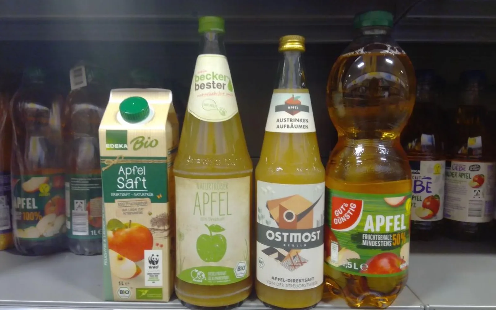 Verschiedene Apfelsaft-Flaschen und Getränkeverpackungen in einem Supermarkt-Regal