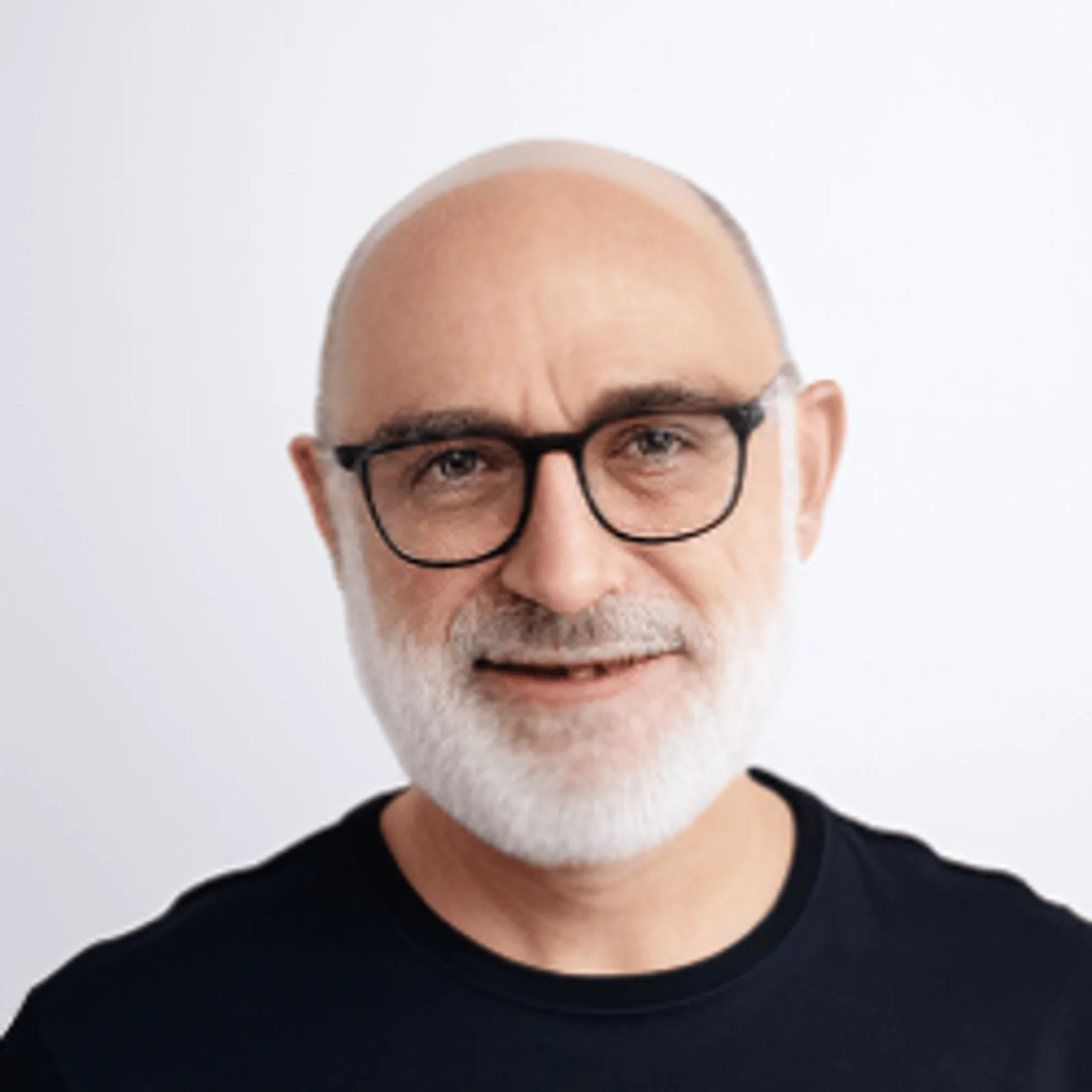 Porträt eines älteren Mannes mit Glatze, weißem Vollbart, schwarzer Brille, schwarzem T-Shirt vor grauem Hintergrund
