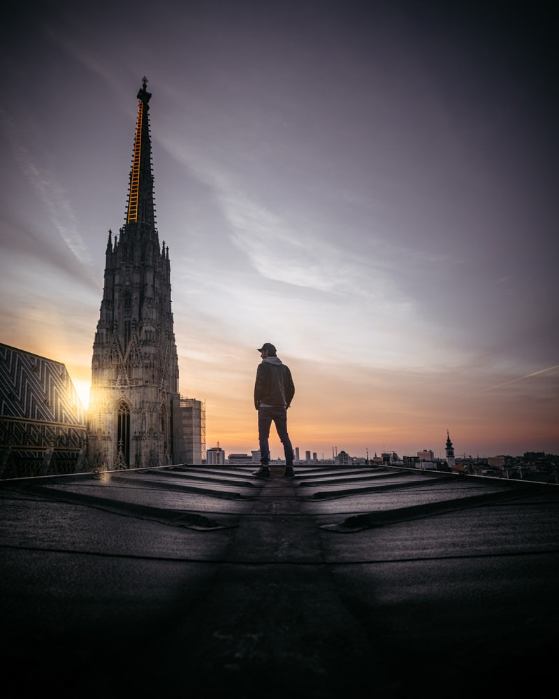 Mann auf Dach des Haas Haus Wien mit Stephansdom im Hintergrund bei Sonnenaufgang