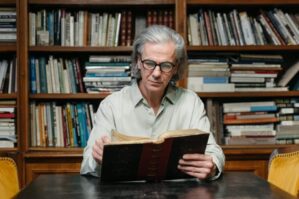 Mann liest vor einem Bücherregal