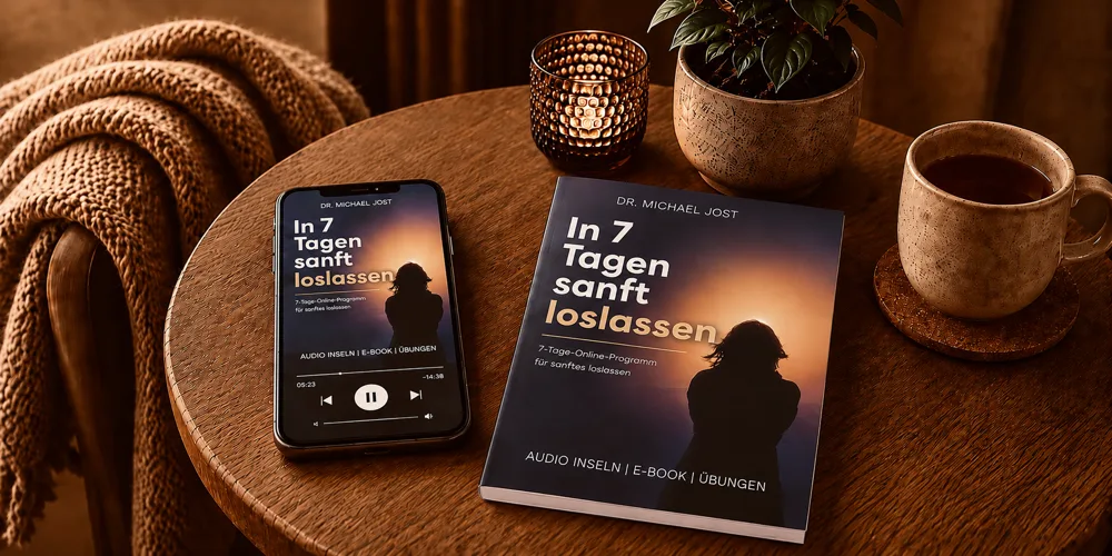 Smartphone und Buch "In 7 Tagen sanft loslassen" auf Holztisch mit Kaffeetasse und Wolldecke