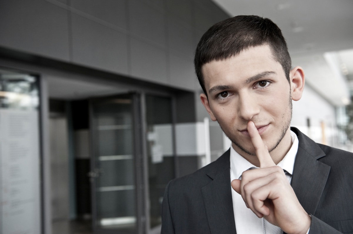 Junger Mann im Geschäftskostüm mit Hand am Kinn, nachdenklich in modernem Büro