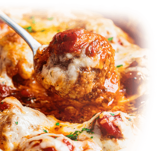 Nahaufnahme von Fleischbällchen in roter Tomatensauce mit Löffel