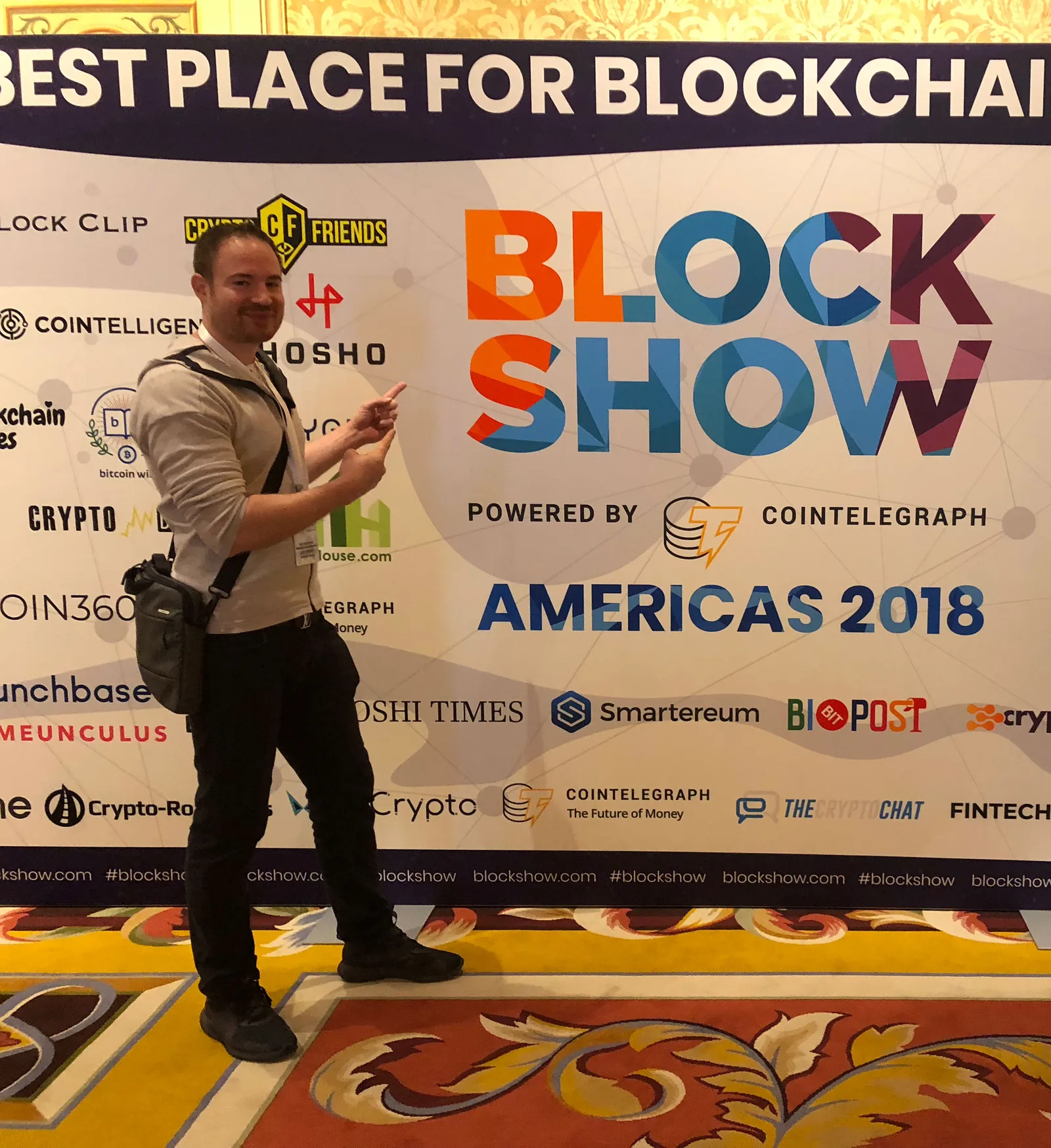 Mann vor Blockshow Americas 2018 Backdrop mit Cointelegraph Logo