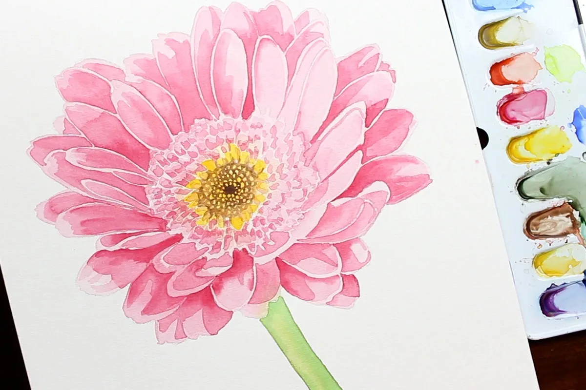 Aquarell Gerbera mit leuchtend rosa Blütenblättern, gelben Zentrum und Aquarellpalette daneben