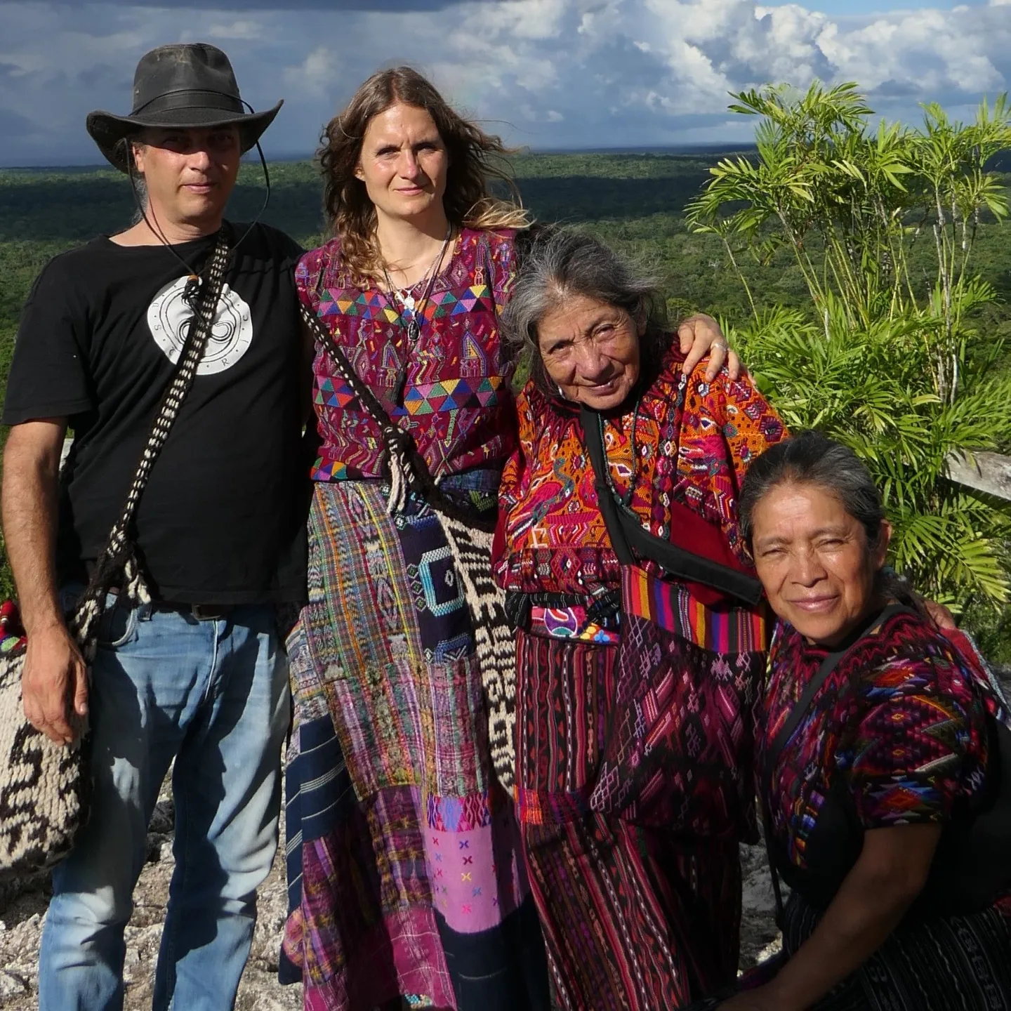 Vier Personen in bunter traditioneller Maya-Kleidung vor grüner Dschungellandschaft