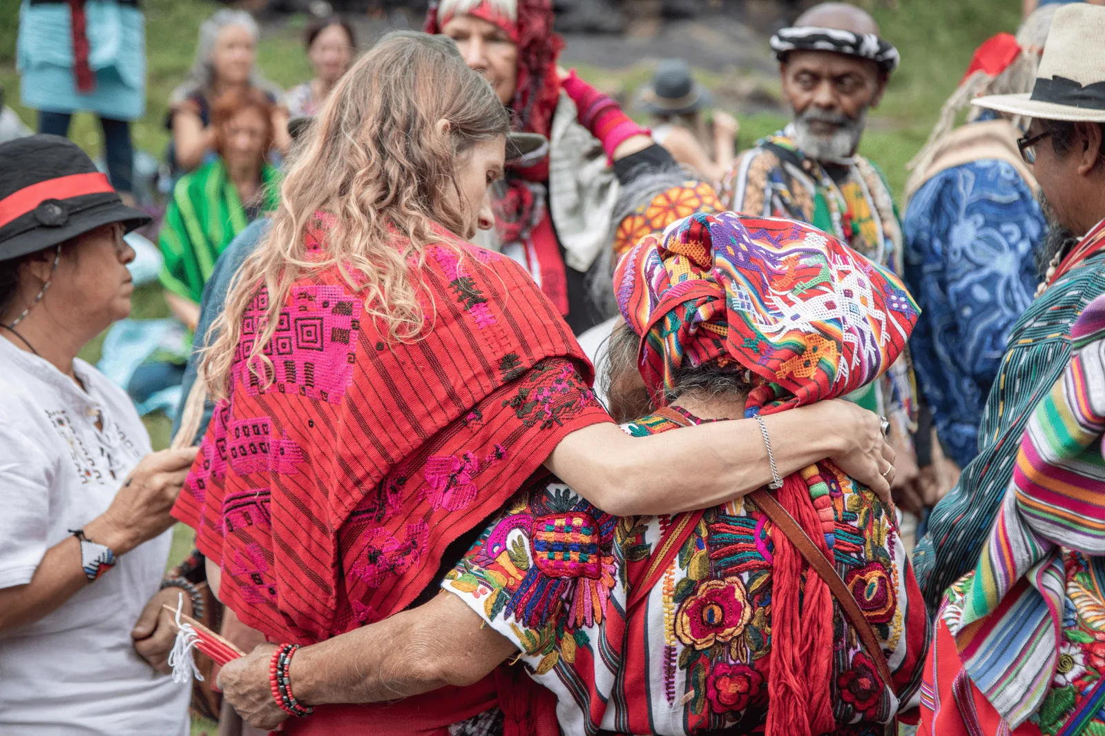 Gruppe von Menschen in traditioneller indigener Kleidung umarmt sich bei einer Zeremonie