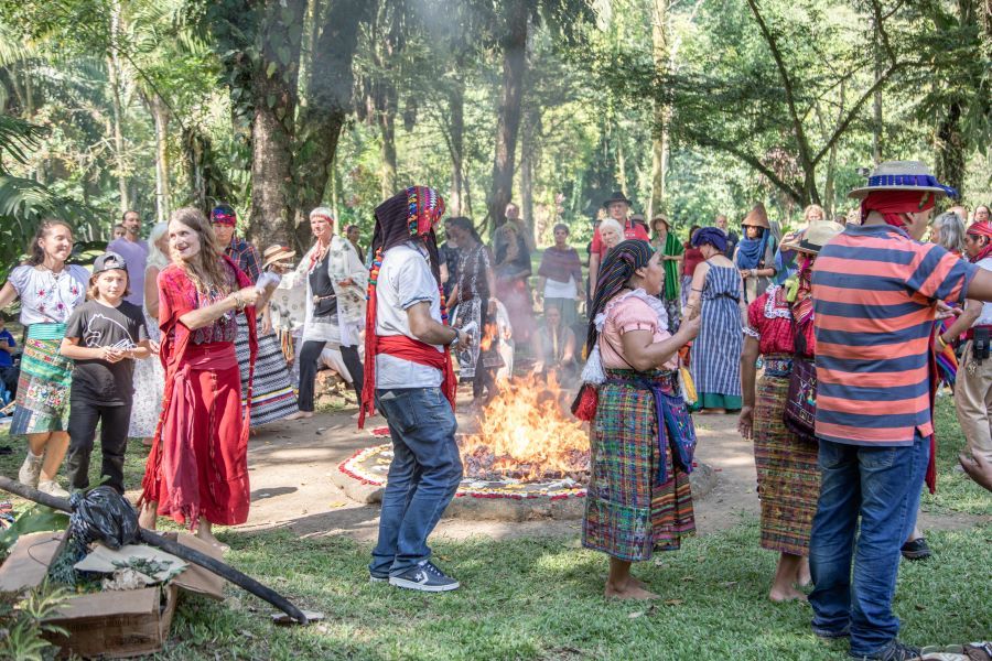 Gruppe von Menschen in traditioneller Maya-Kleidung bei kulturellem Ritual mit Feuer