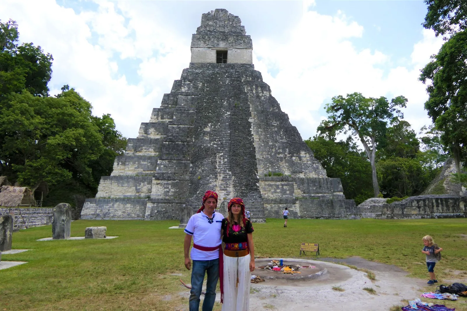Zwei Personen in traditioneller Kleidung vor der Ruine der Tikal-Pyramide