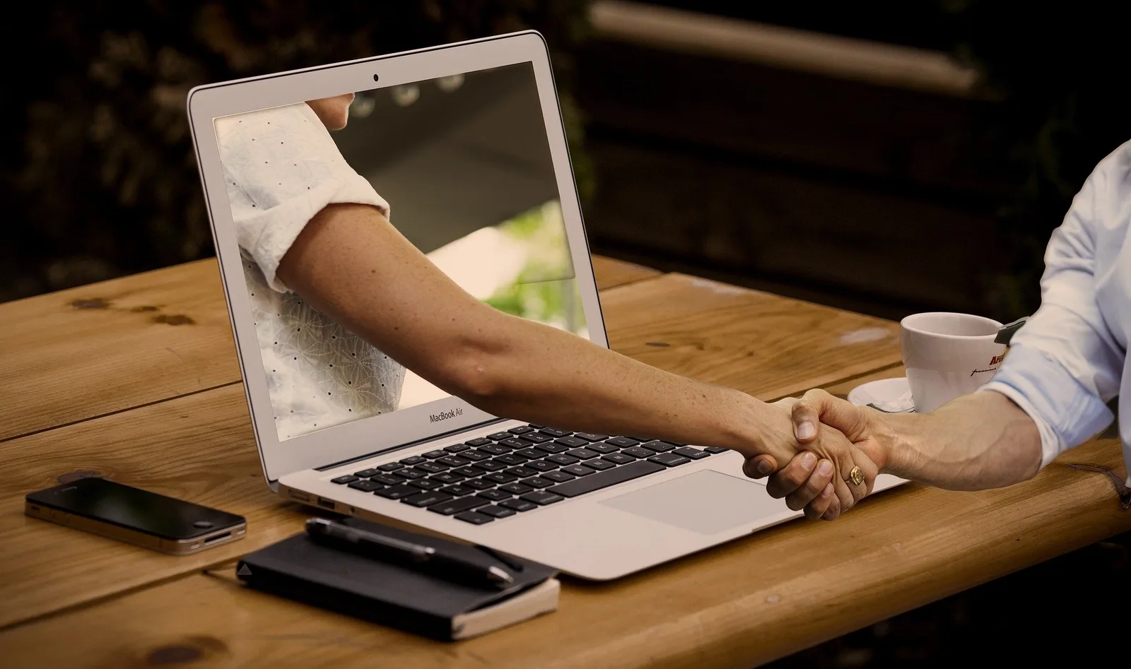 Webinar-Szenerie mit Laptop und Handshake beim virtuellen Meeting