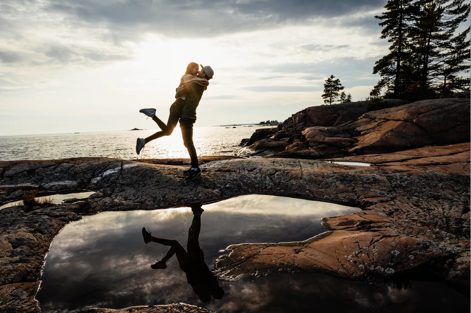 Paar springt auf Felsen mit warmem Preset-Filter, intensivere Farbtöne, Meer und Landschaft