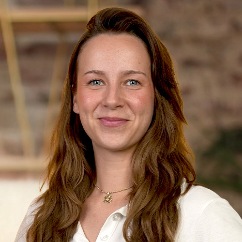 Porträt von Laura Michalski, Coach mit braunen Haaren und weißem Oberteil