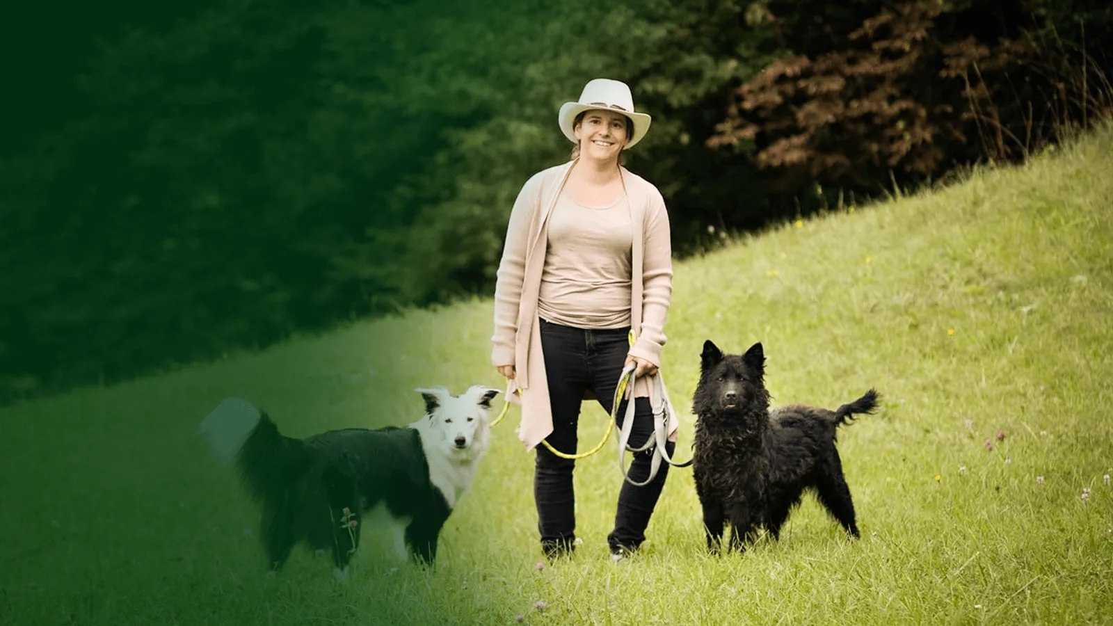 Sarah Fink Hundetrainerin mit zwei Hunden auf Wiese im grünen Gelände