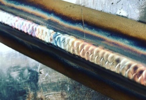 Detailaufnahme einer WIG-Schweißnaht mit mehrfarbiger Färbung auf Stahlrohr