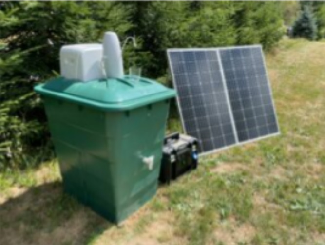 Grüne Wassertonne mit Solarpanel und Pumpe im Freien