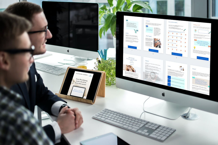Zwei Personen schauen auf Workbook-Seiten auf einem Desktop-Monitor