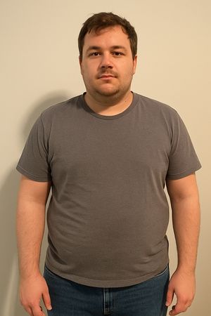Mann in grauem T-Shirt und Jeans vor heller Wand, vorher-Foto