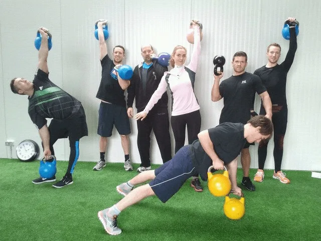 Sechs Personen demonstrieren verschiedene Kettlebell-Übungen mit bunten Kettlebells