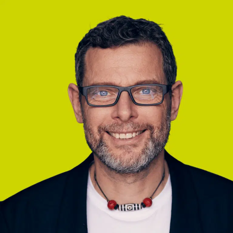 Torsten J. Koerting, Kursautor, Portrait vor neongelben Hintergrund mit Brille und Kette
