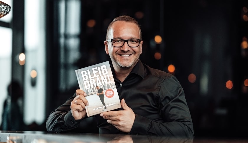 Marko Slusarek präsentiert Bleib Dran Buch lächelnd