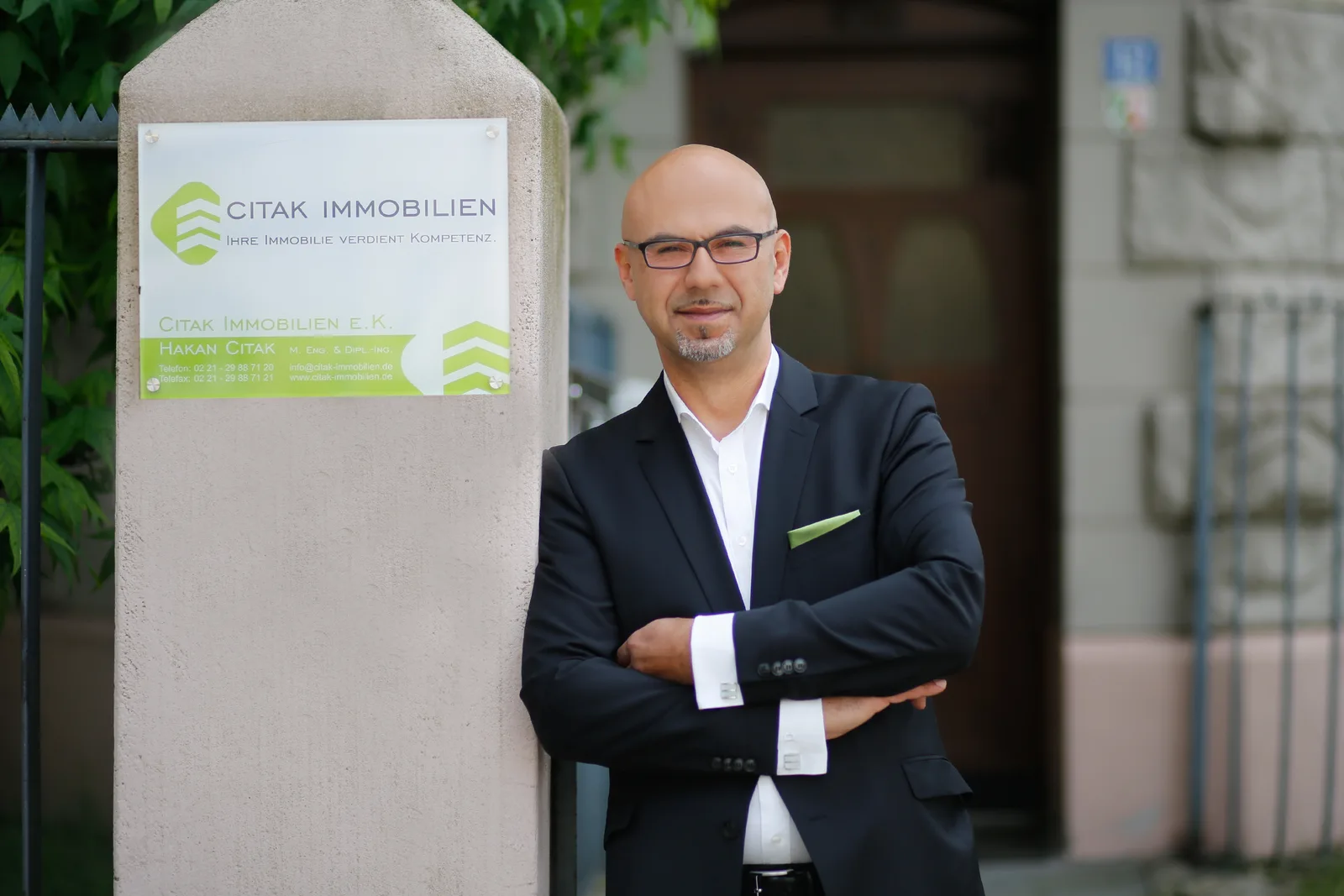 Kickstart Passives Einkommen – Buch zum Online-Business-Aufbau 7 Hakan Citak Immobilienmakler vor Büroschild in Business-Anzug