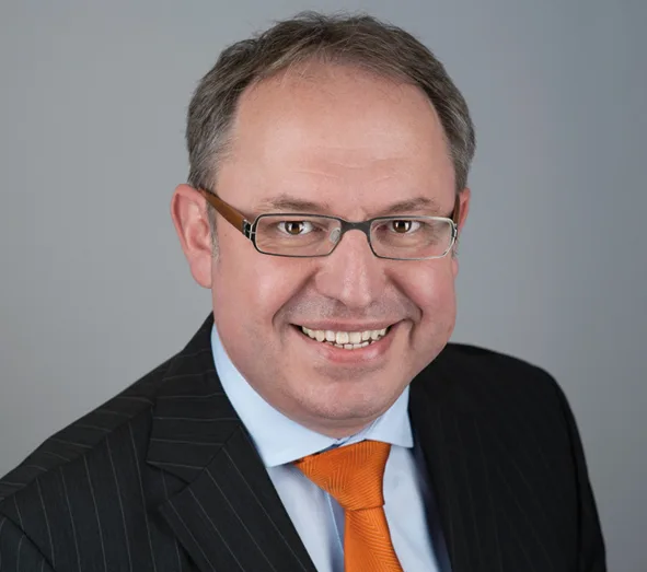 Kickstart Passives Einkommen – Buch zum Online-Business-Aufbau 10 Alexander Krunic Business-Porträt mit Brille in blauem Hemd und orangener Krawatte