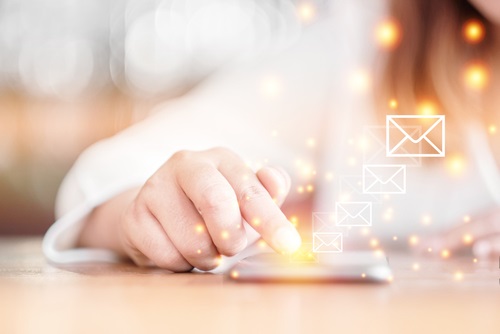 Hand auf Smartphone mit leuchtenden E-Mail-Symbolen