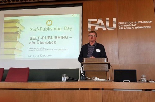 Dr. Lutz Kreutzer spricht beim Self-Publishing-Day an Podium vor Publikum