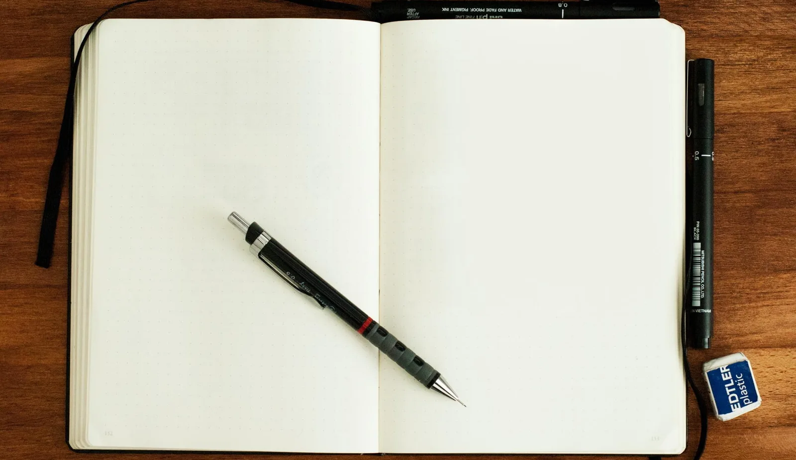 Offenes Notizbuch auf Holztisch mit Stift, Lineal und Radiergummi