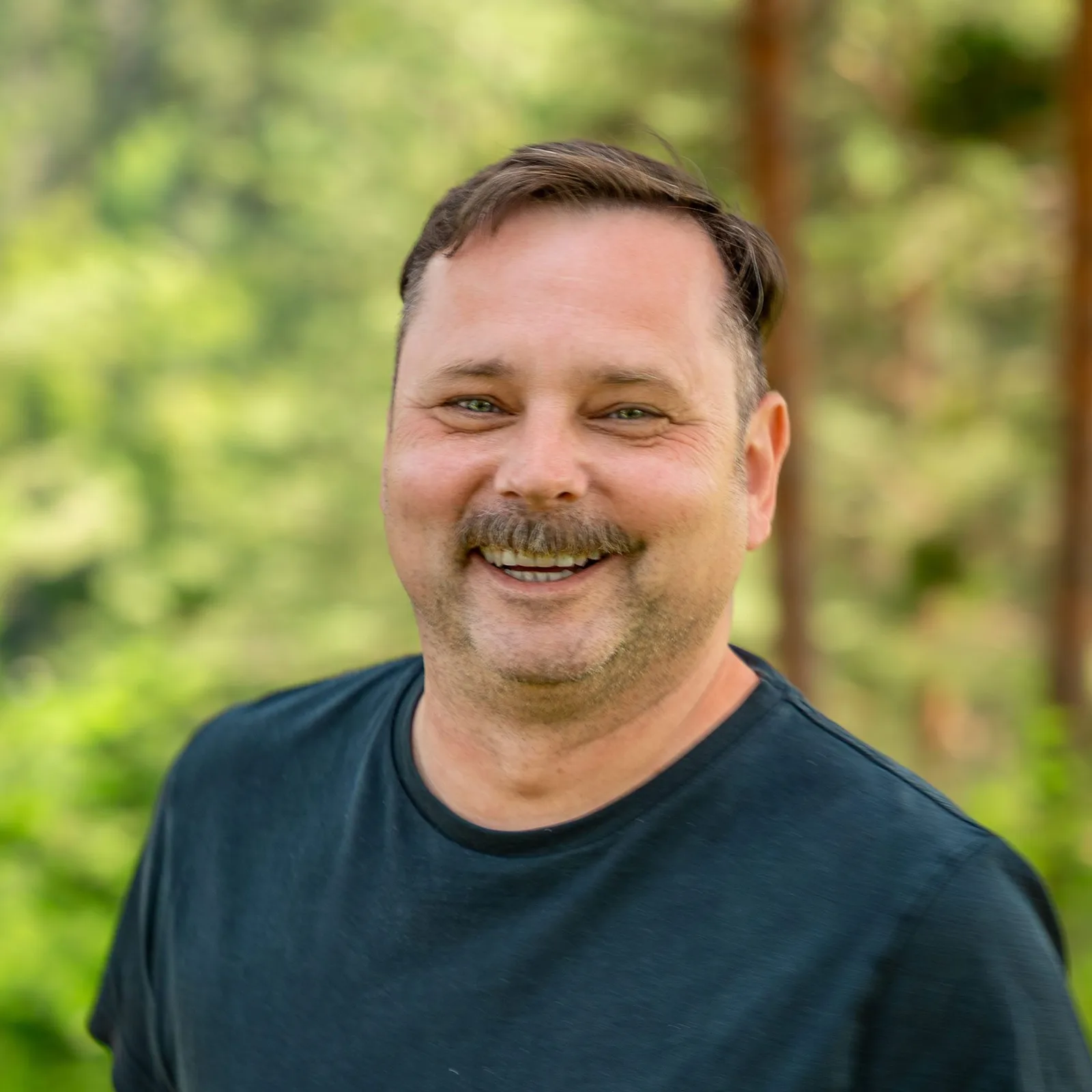 Mike, männliches Porträt mit Schnurrbart, dunkles Shirt, grüner Hintergrund, Support-Team