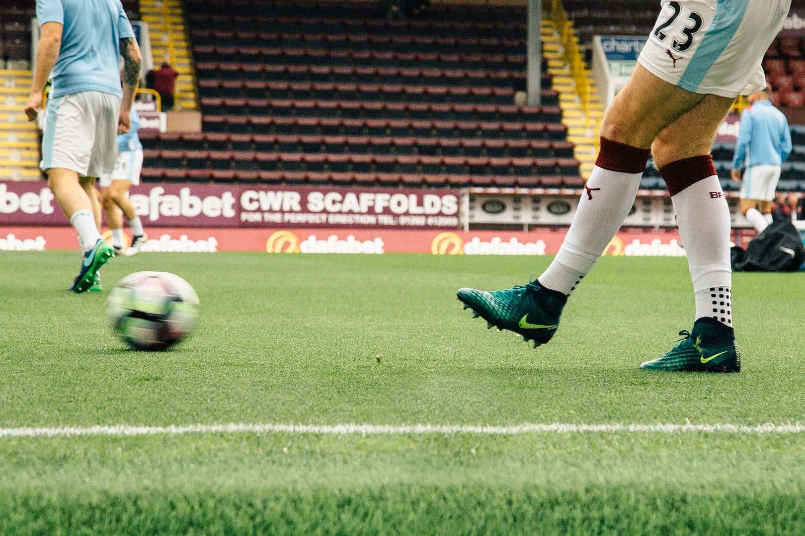 Fußballspieler in weißem Trikot mit Ball im Stadion