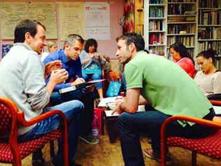 Gruppe von Menschen sitzt im Kreis in einem Klassenzimmer und diskutiert während eines NLP-Coachings