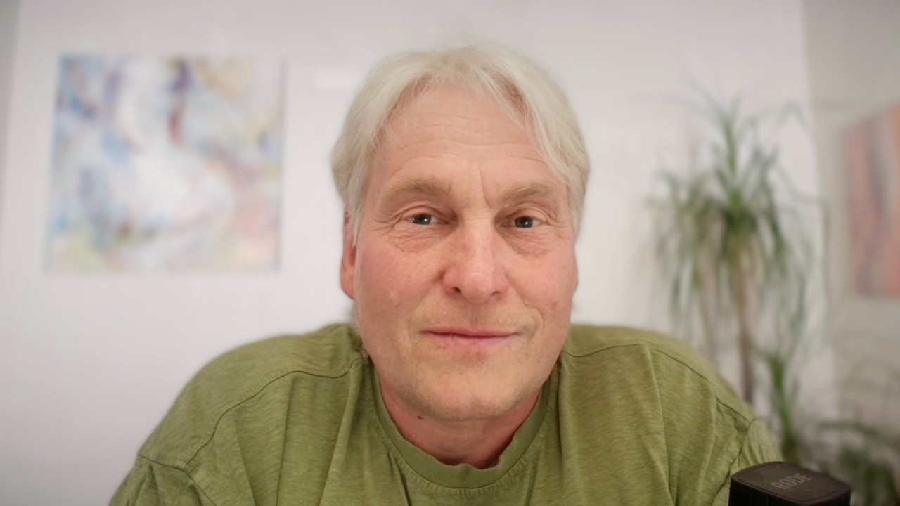 Mann mittleren Alters mit grünem Shirt und hellem Haar vor unscharfem Hintergrund
