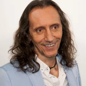 Bruno Wuertenberger mit langen dunklen Haaren und Bart in hellblauem Blazer