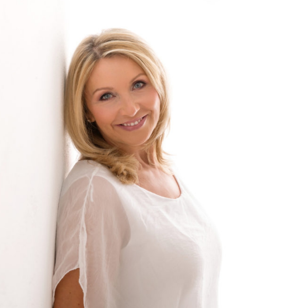 Pavlina Klemm blonde Frau in cremefarbenem Oberteil vor weißem Hintergrund lächelnd