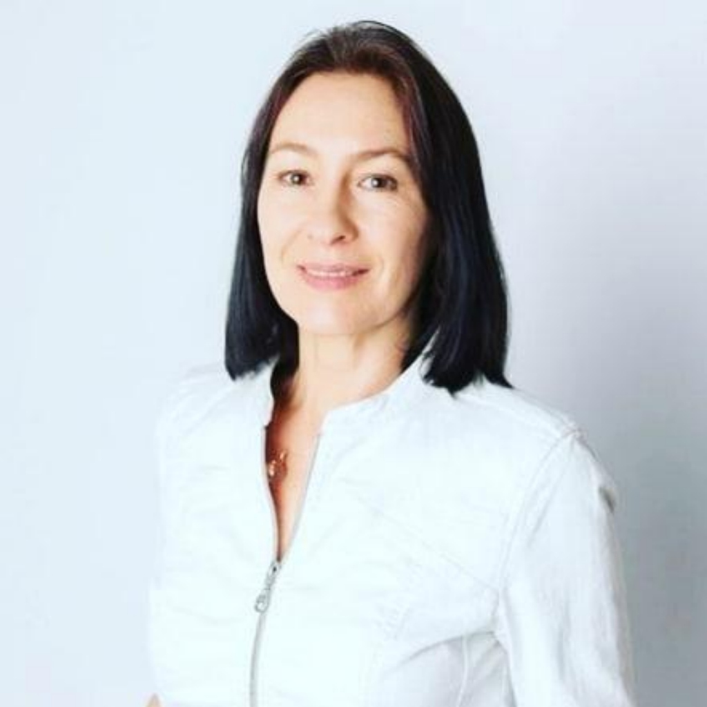 Portrait Lumira, Frau mit schwarzem Haar und weißer Bluse vor hellem Hintergrund