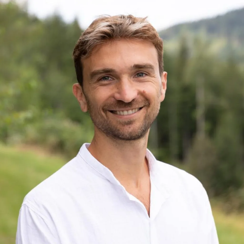 Portrait Ricardo, Mann mit braunem Haar in weißem Hemd vor grüner Naturkulisse