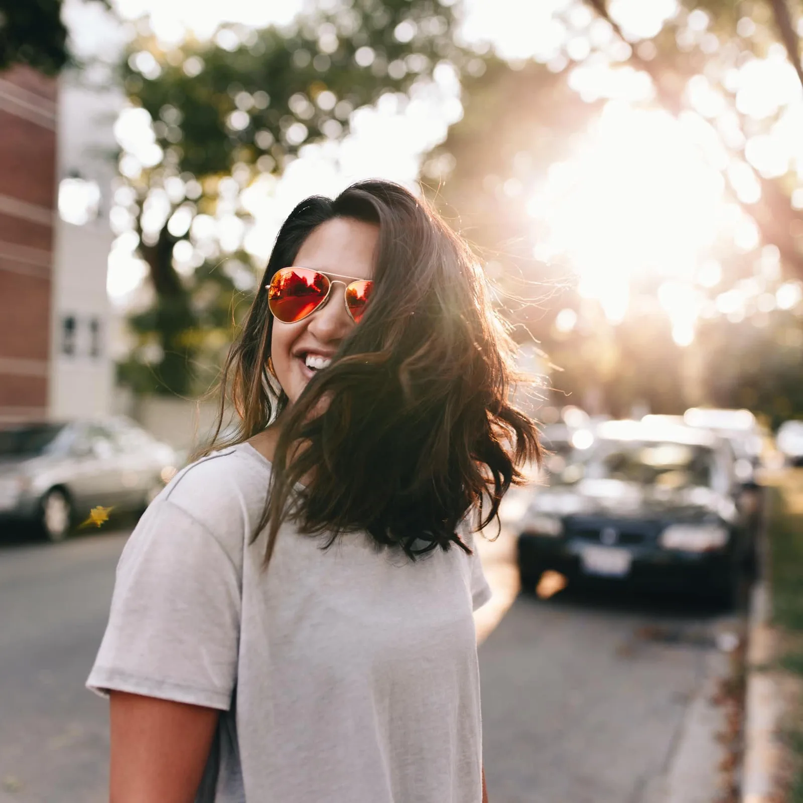 Frau mit herzförmiger Sonnenbrille und weißem Shirt in Stadtumgebung
