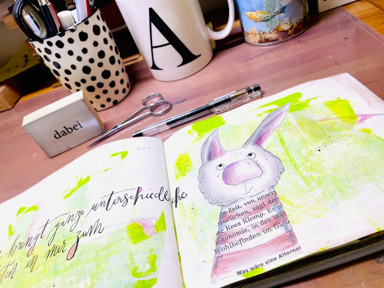 Offenes Kunstjournal mit Illustrationen, Aquarellmalerei und handschriftlichem Text auf rosa Oberfläche