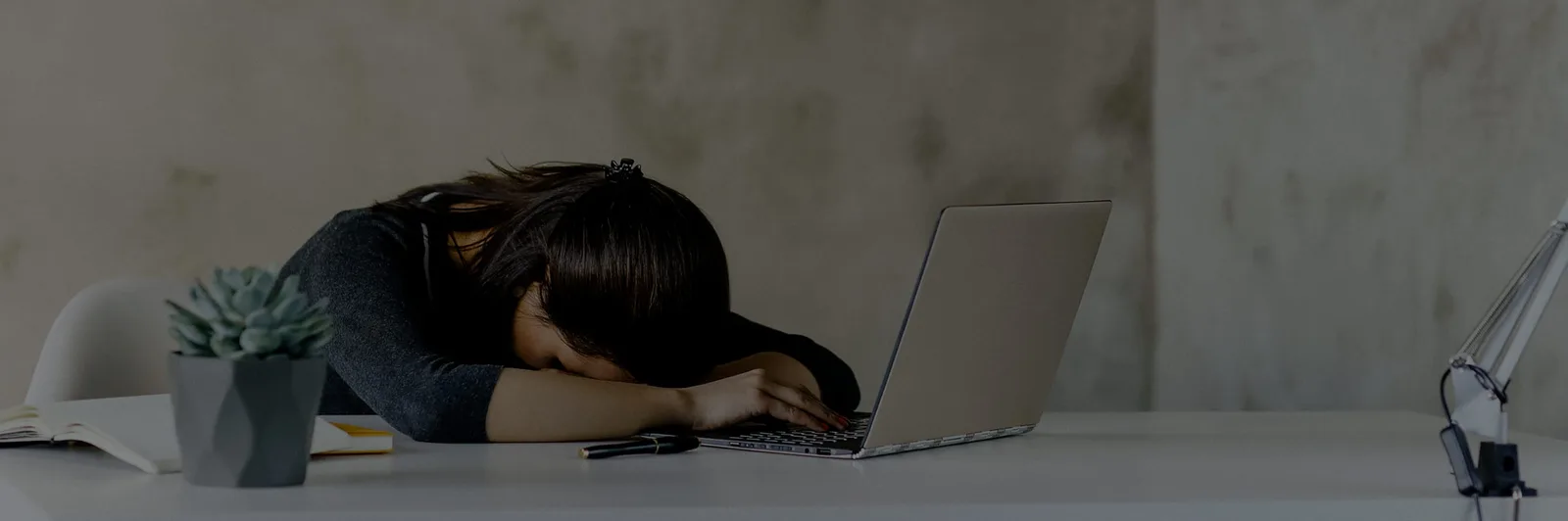 Person erschöpft am Laptop mit Kopfschmerzen und administrativer Arbeit symbolisierend Bürokram