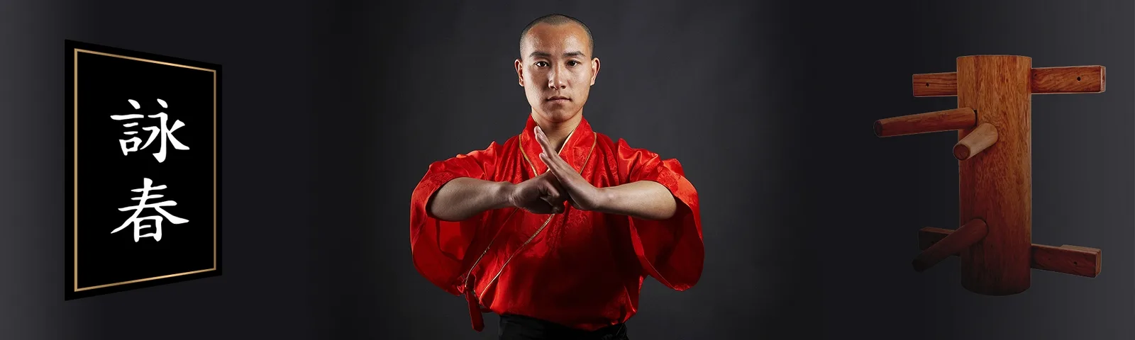 Wing-Chun-Meister in rotem Anzug mit Kampfposition vor asiatischen Symbolen und Holzgerät
