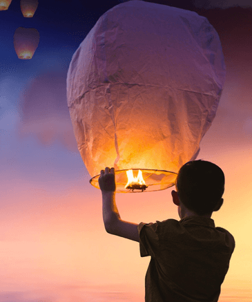 Junge hält leuchtenden Himmelslaternen vor Sonnenuntergang-Himmel