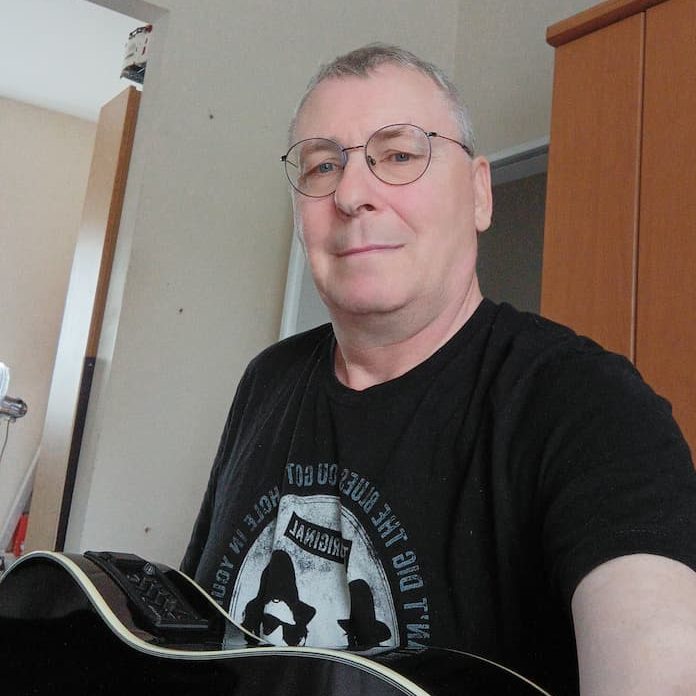 Klaus Schlünz mit Akustikgitarre Portrait mit Brille
